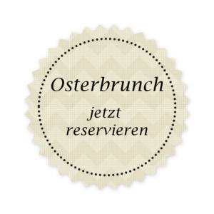 Ein rundes Schild mit beigem Zickzack-Hintergrund und gepunktetem Rand zeigt den Text „Osterbrunch jetzt reservieren“ in schwarzen Buchstaben vor einem grauen Gittermuster und wirbt für das wunderbare Angebot des Hotels Bienenberg.